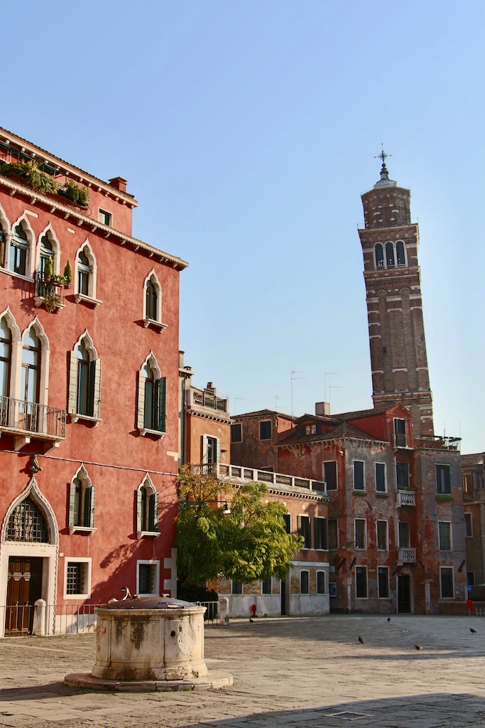 Le Campo Sant Angelo à Venise avec des façades de palais, un puits et le clocher penché de l'église Santo Stefano.