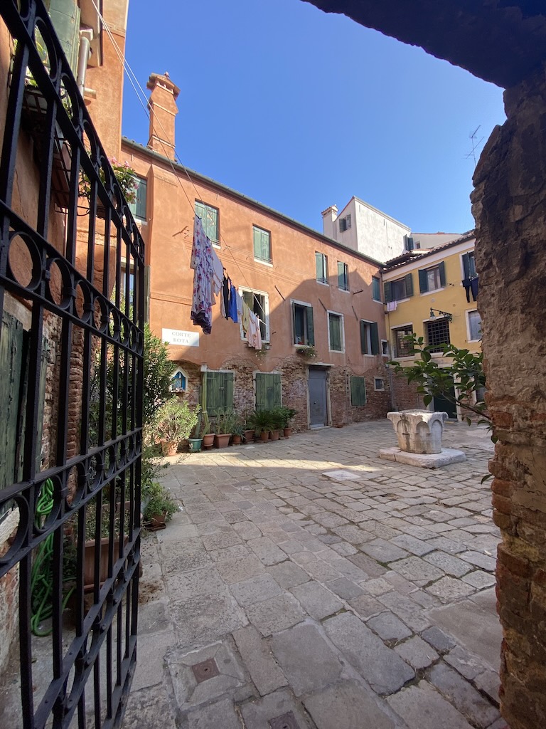 Une cour intérieure d'immeuble à Venise avec un puit et du linge qui sèche sur le fil. 